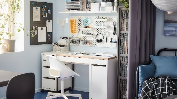 A desk with swivel chair and a wall-mounted shelf and a pegboard